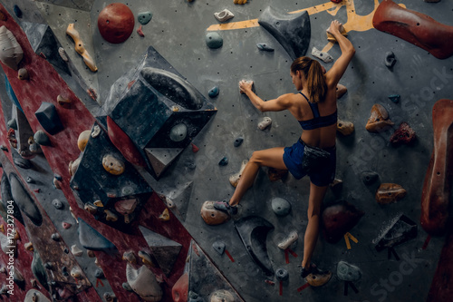 Free climber female bouldering indoors.