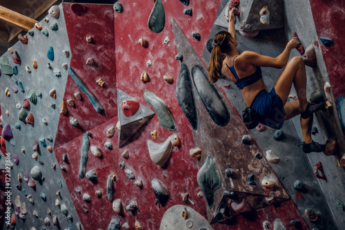 Free climber female bouldering indoors.