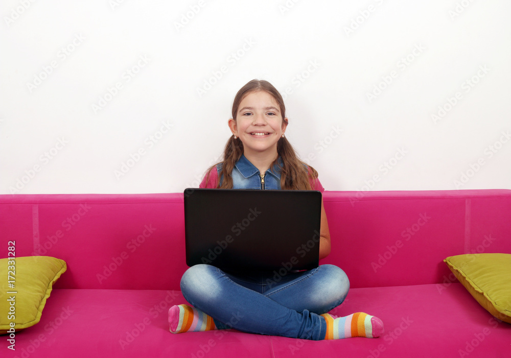 happy little girl with laptop sitting on bed happy little girl with laptop sitting on bed