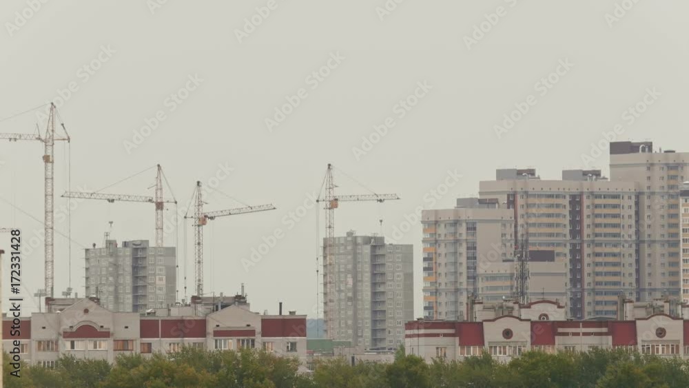 Residential houses - workers on construction site - building new living district, telephoto Residential houses - workers on construction site - building new living district, telephoto