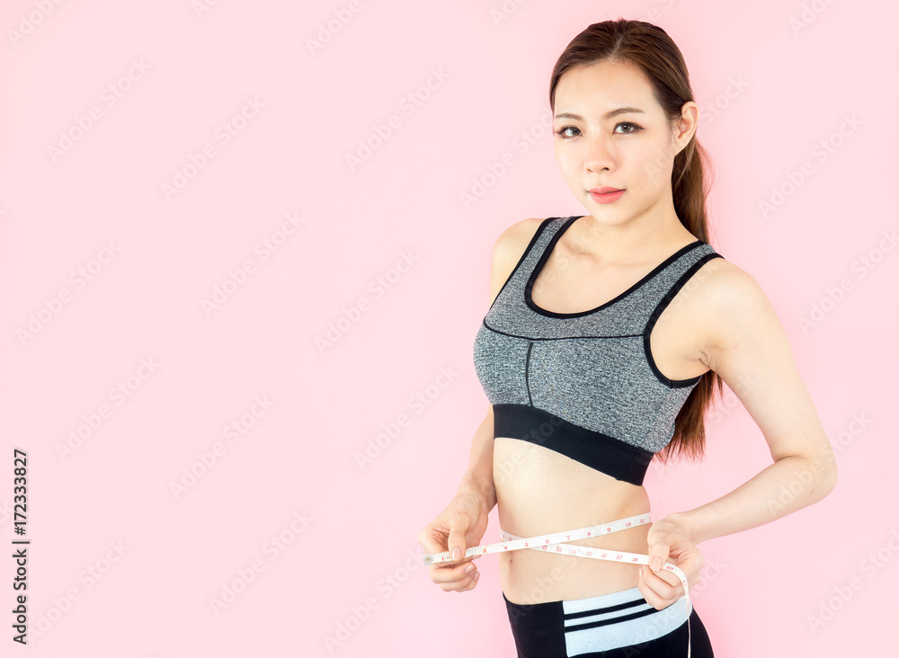 Young asian beautiful woman with sport fitness concept, workout, exercise, measure tape at waist on pink background Young asian beautiful woman with sport fitness concept, workout, exercise, measure tape at waist on pink background