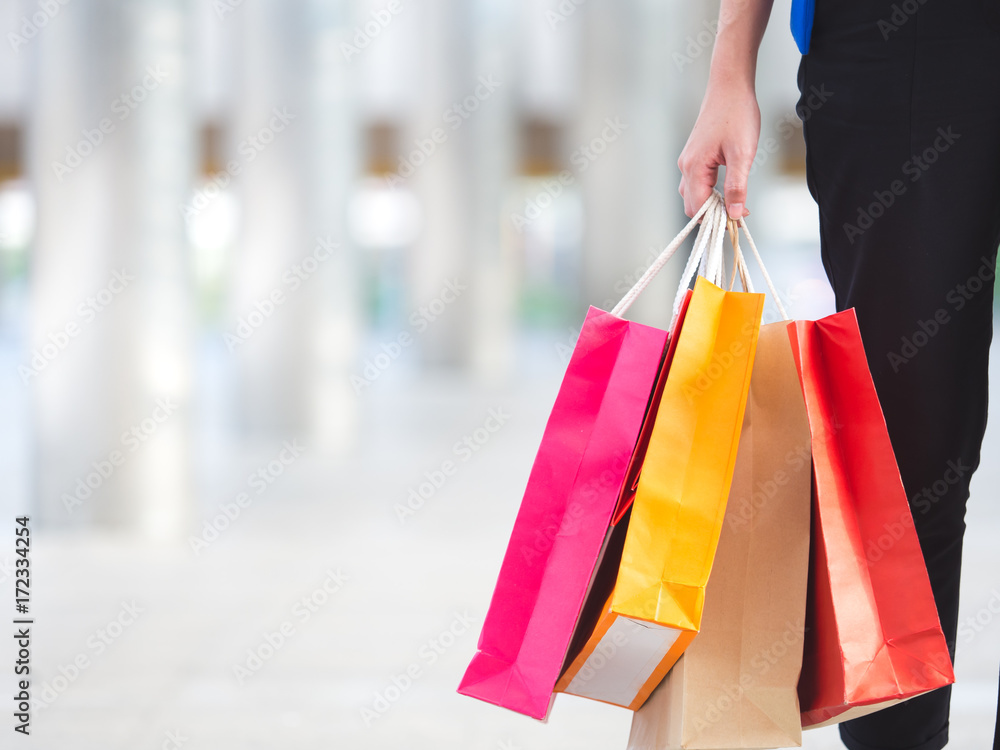 Close up woman holding shopping bag with colorful walking in the city with copyspace