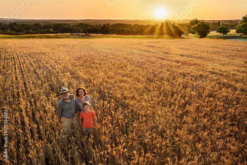 Farmer family standing in their wheat field at sunset