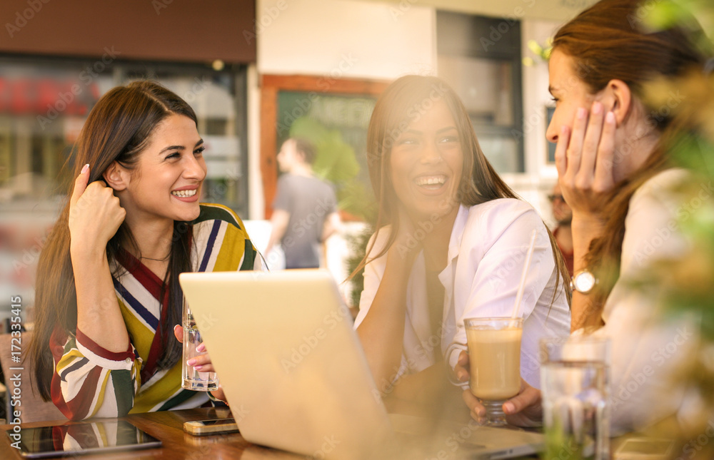 Three young women having conversation in cafe and using laptop. Three young women having conversation in cafe and using laptop.
