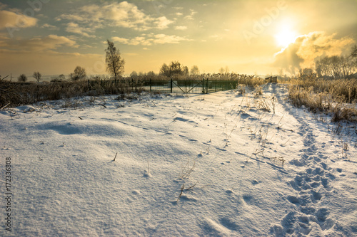 Winter landscape with footprints in snow before sunset