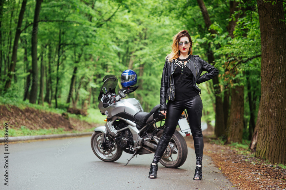 Obraz premium An attractive sexy girl on a sports motorbike posing outside