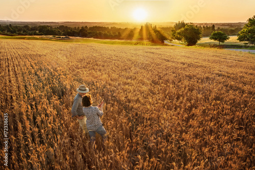 Farmer couple standing in their wheat field at sunset