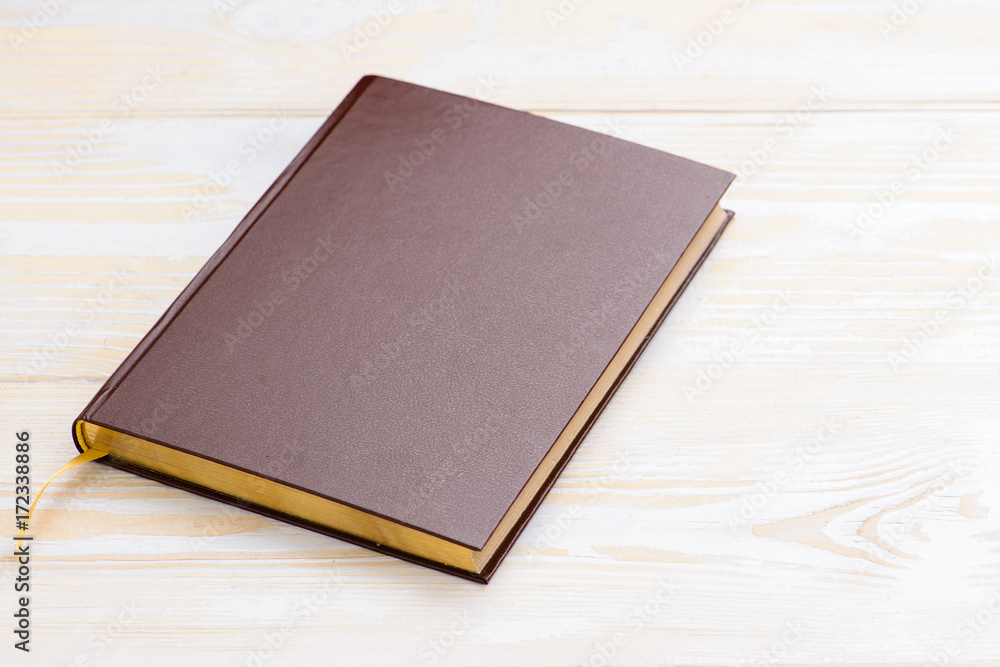 Close-up of brown book on wooden background Close-up of brown book on wooden background