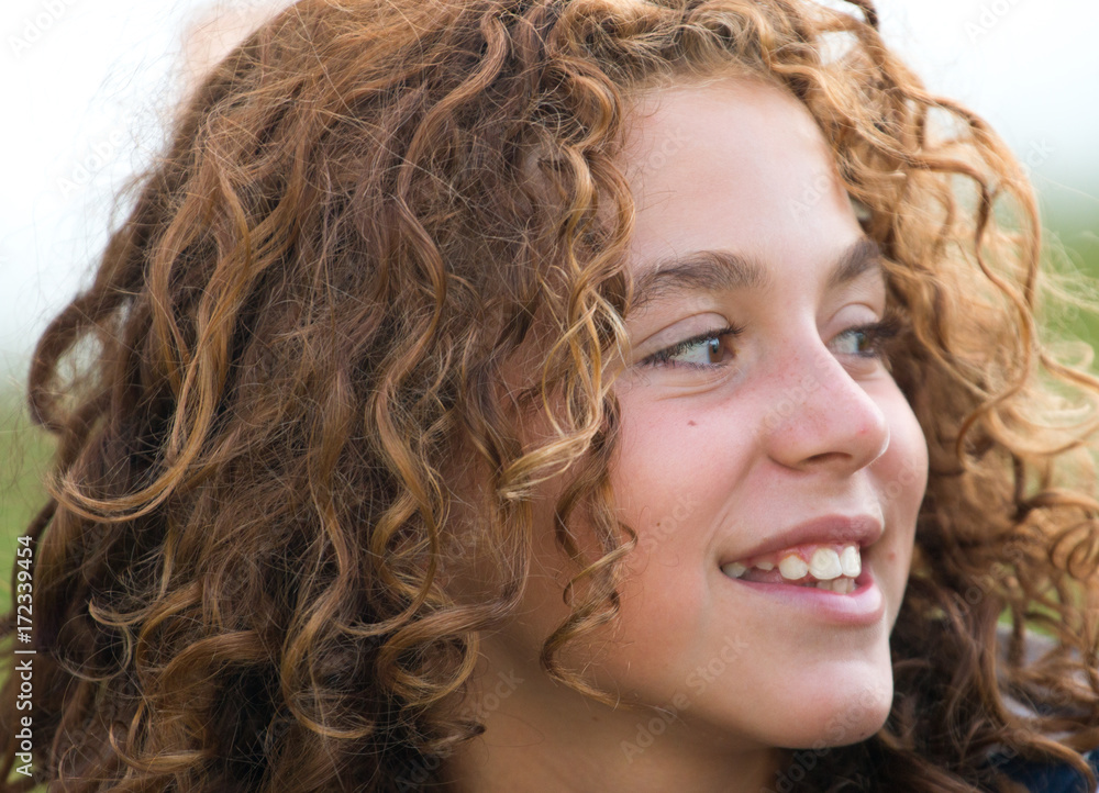 Close-up of a girl with curly hair, happy, smiling and on vacation Close-up of a girl with curly hair, happy, smiling and on vacation
