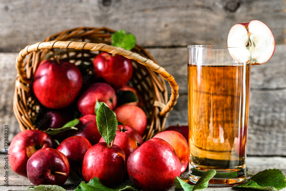 Delicious apple juice in a cup and red apples on wooden table, organic food and healthy lifestyle concept Delicious apple juice in a cup and red apples on wooden table, organic food and healthy lifestyle concept