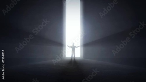 Man standing at an opening light tunnel's entrance raising his hands up
