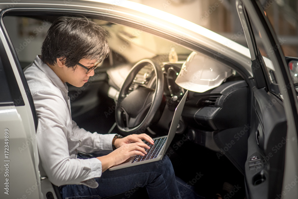 Young Asian Engineer or Architect working with laptop computer while sitting in his car. Mechanical engineering and building construction concepts Young Asian Engineer or Architect working with laptop computer while sitting in his car. Mechanical engineering and building construction concepts