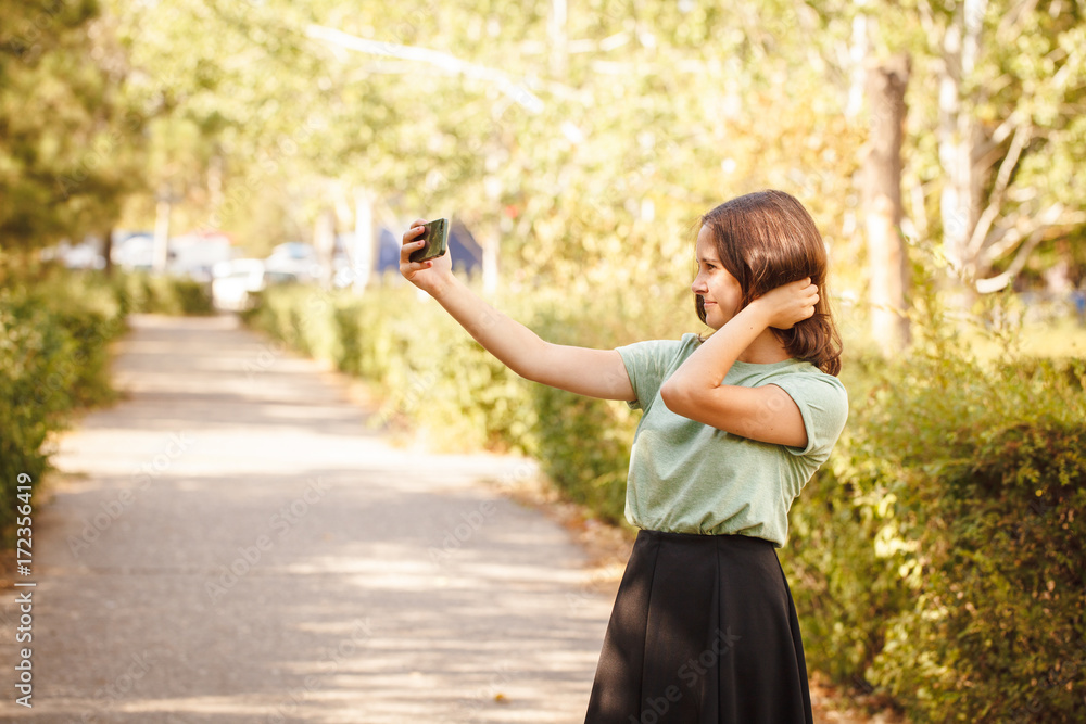 A young teenage girl outdoors doing selfie. A young teenage girl outdoors doing selfie.