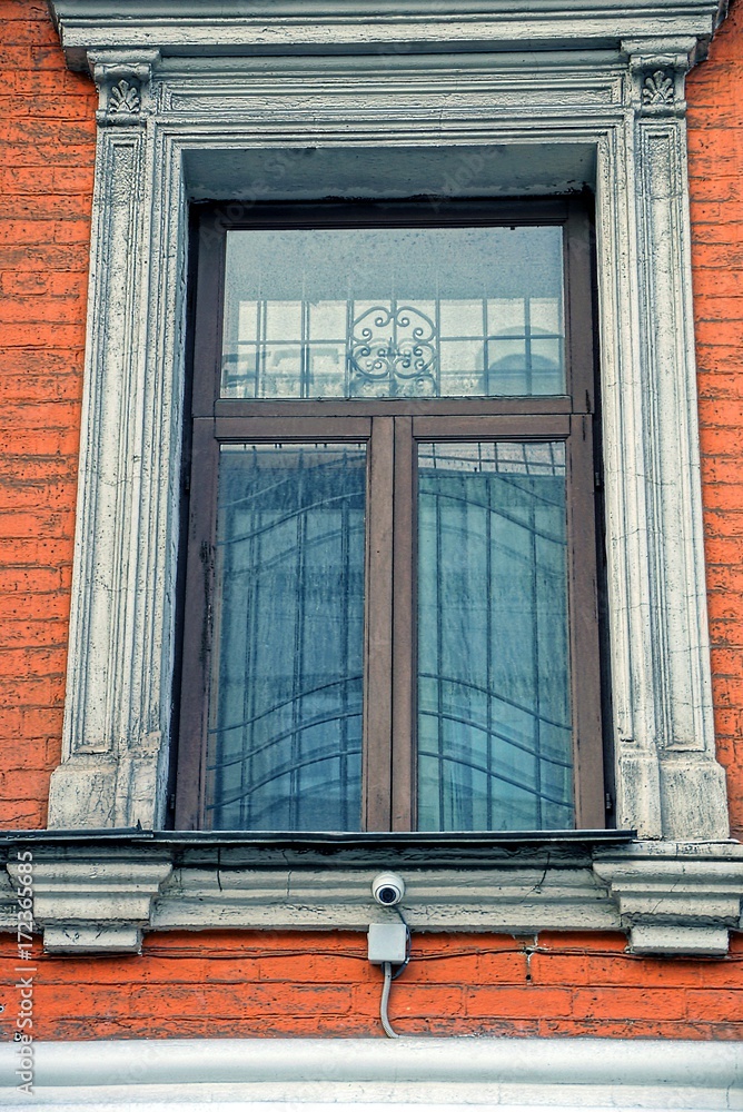 Старое окно с решёткой на кирпичной стене жилого дома