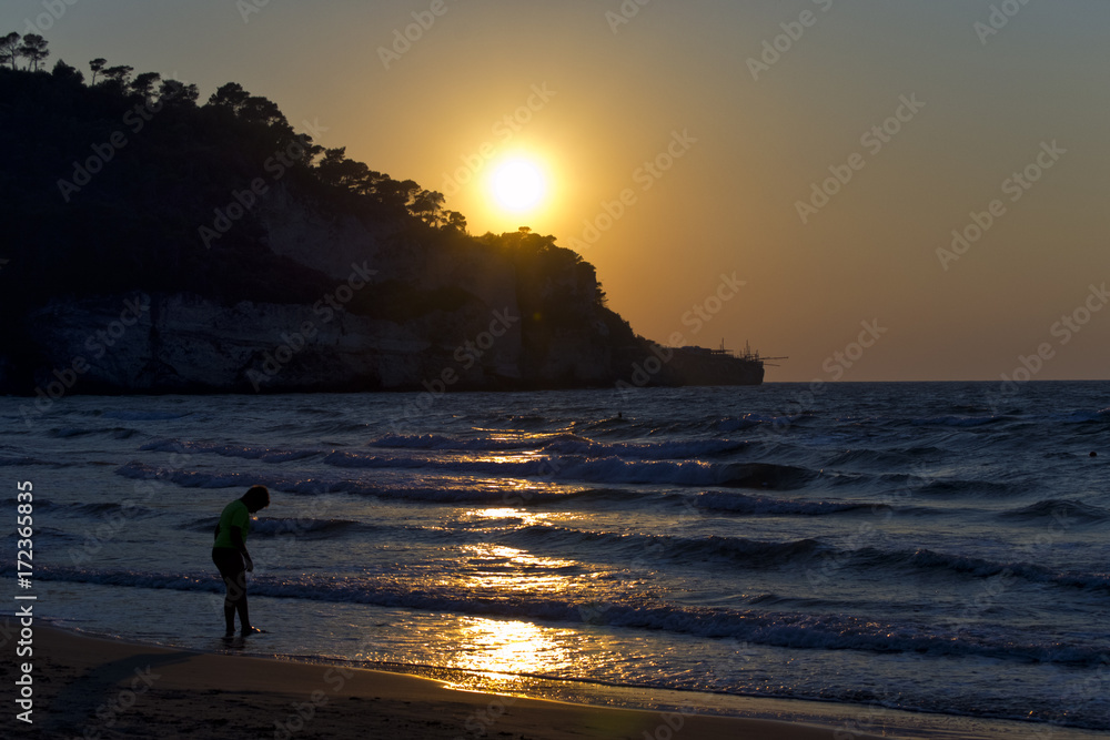 silhouette of a boy on foreshore during sunset. for vacation and summer holiday concept