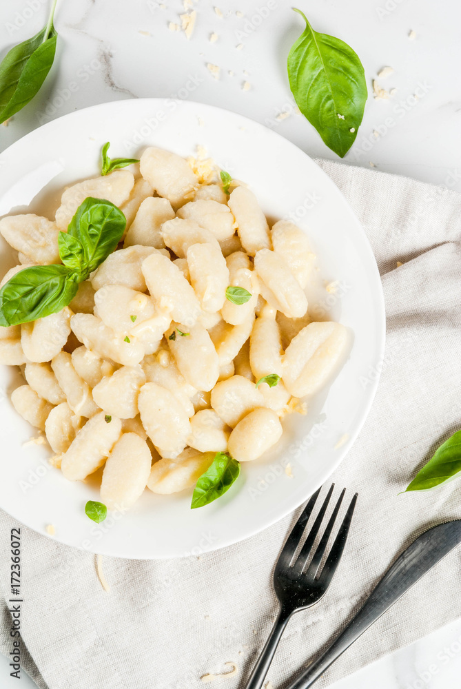 Italian food recipe, Healthy vegan dinner with potato gnocchi. With grated parmesan cheese, basil and pesto sauce. On white marble , copy space top view Italian food recipe, Healthy vegan dinner with potato gnocchi. With grated parmesan cheese, basil and pesto sauce. On white marble , copy space top view