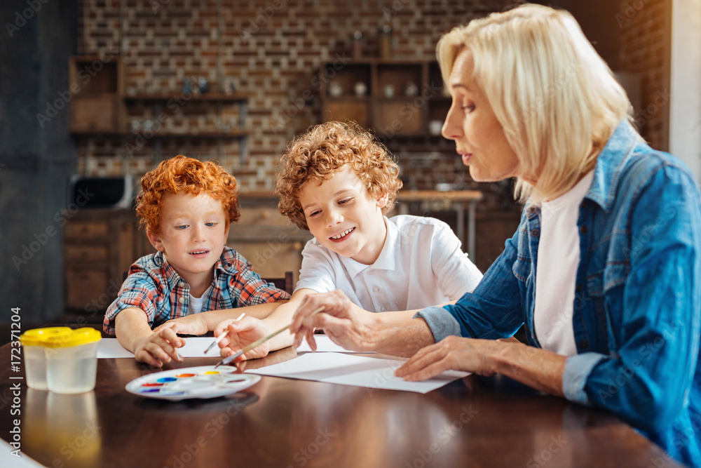 Mindful senior lady painting with grandchildren at home