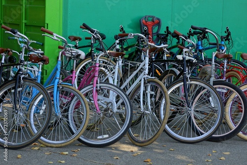 Множество цветных велосипедов стоят на стоянке у стены
