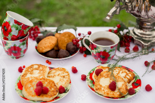 Самовар с чашками и десертом с малиной на столе в саду. Завтрак на природе 