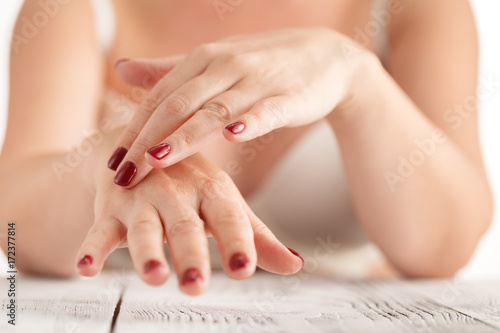 Women s hands with red manicure to apply the cream