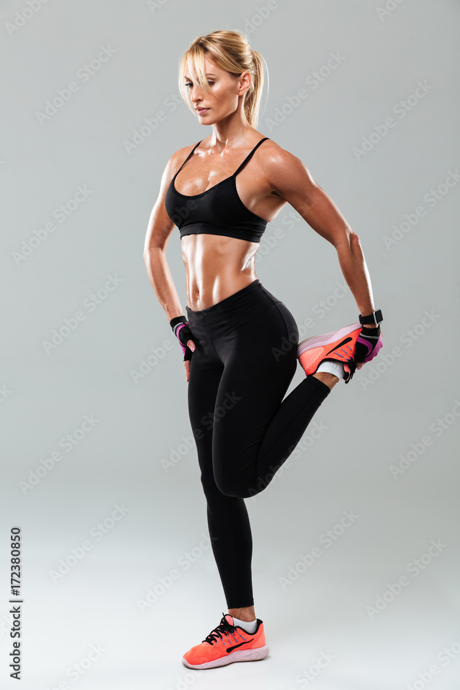 Full length portrait of a pretty sportswoman doing stretching exercises Full length portrait of a pretty sportswoman doing stretching exercises