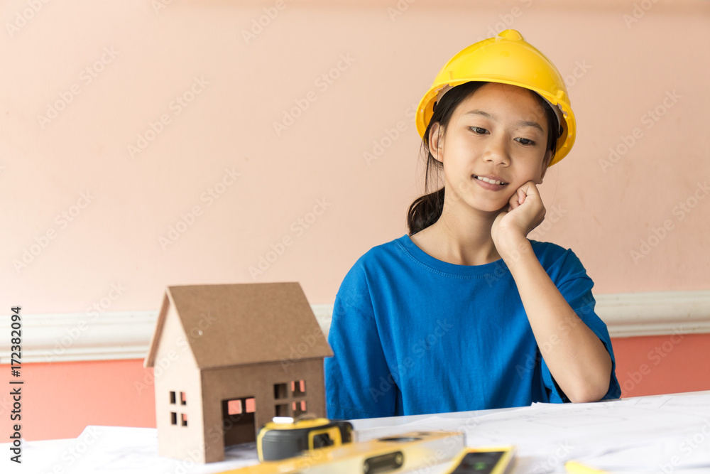 Asian girl has ambition to be a structural engineer with a helmet and the building plan put on the table. Asian girl has ambition to be a structural engineer with a helmet and the building plan put on the table.