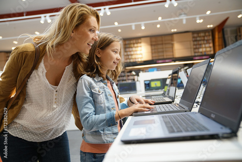 Mother and daughter looking at laptop in multimedia store photo