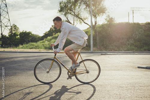 Young handsome hipster man riding fixed gear bicycle during sunset