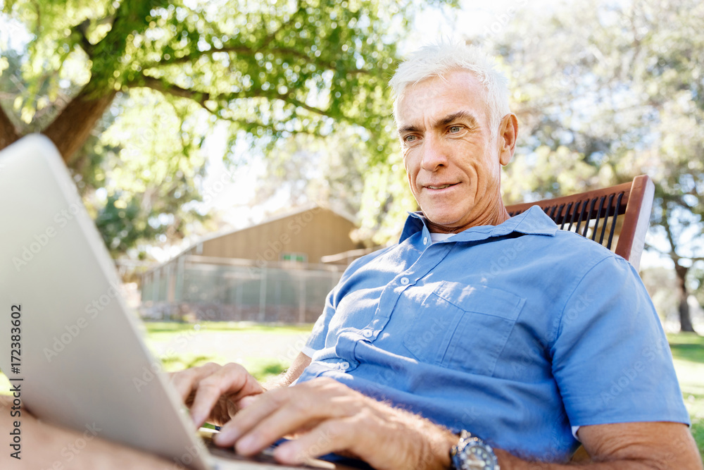 Senior man with notebook sitting in the park Senior man with notebook sitting in the park