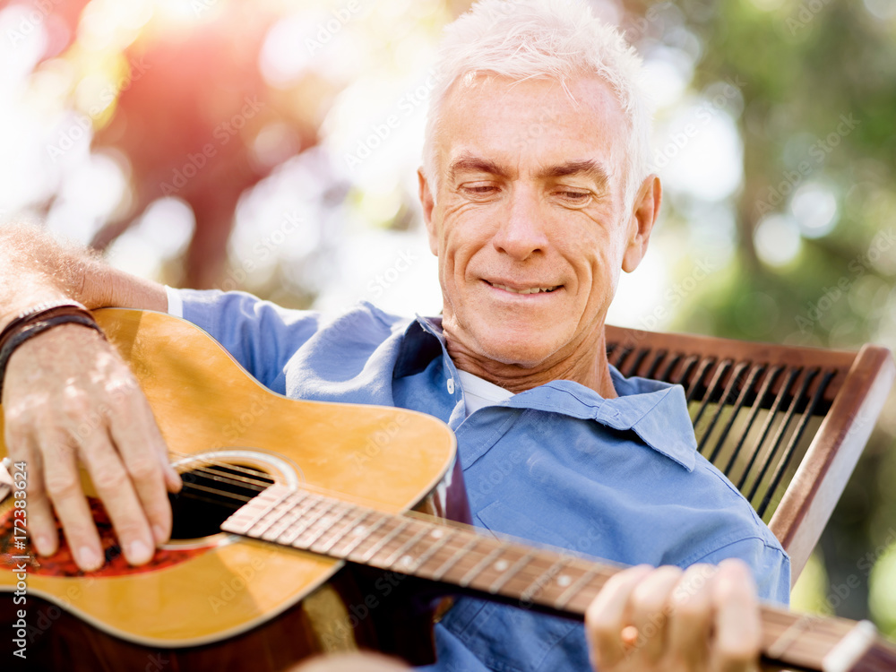 Senior man plying guitar outdoors Senior man plying guitar outdoors