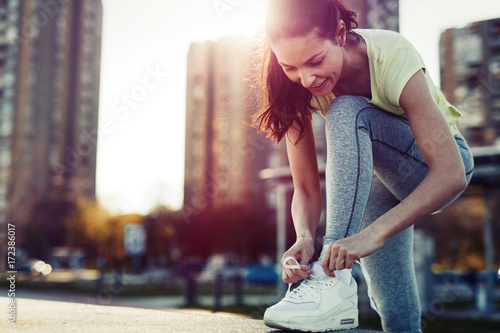 Fotografie Attractive sportswoman tying shoelace and getting ready for fitness