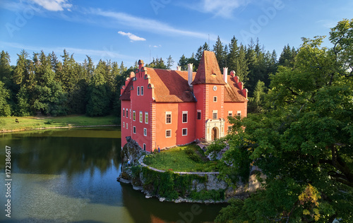 Aerial view of bizarre water castle Cervena Lhota, picturesque renaissance-style red château standing at the middle of a lake on a rocky island in the czech landscape, south Bohemia, Czech Republic.