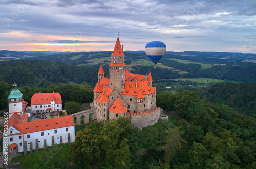 Aerial view on romantic fairytale castle Bouzov with hot air balloon next to highest tower in picturesque czech landscape. Bouzov castle, Moravia, Czech republic. photo