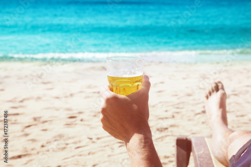 Man holding Glass mug of beer on a beach