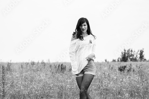 Pretty woman in a white knitted sweater, shorts and boots, stylishly dressed in a field in the fall. A nice and sexy look for beautiful walks and dates at autumn