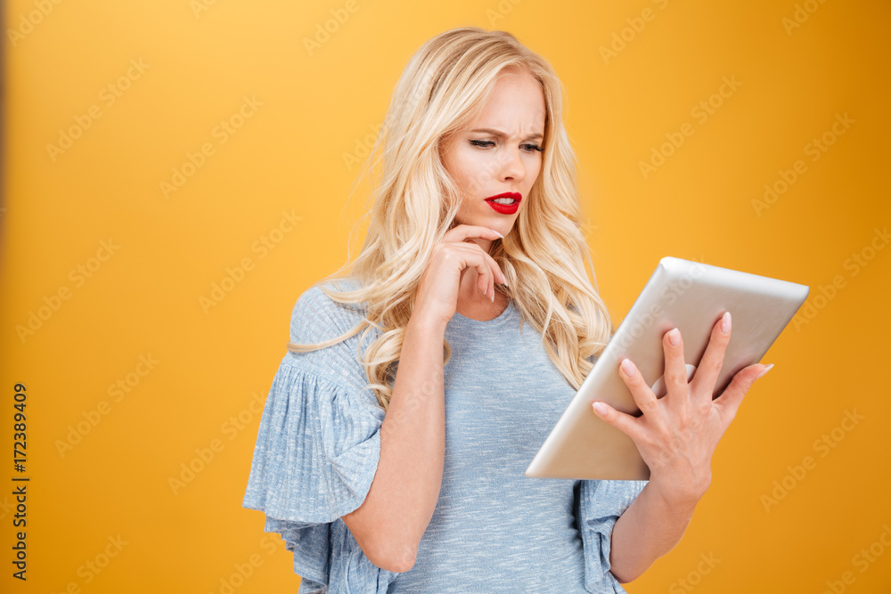 Confused young blonde woman using tablet computer. Confused young blonde woman using tablet computer.