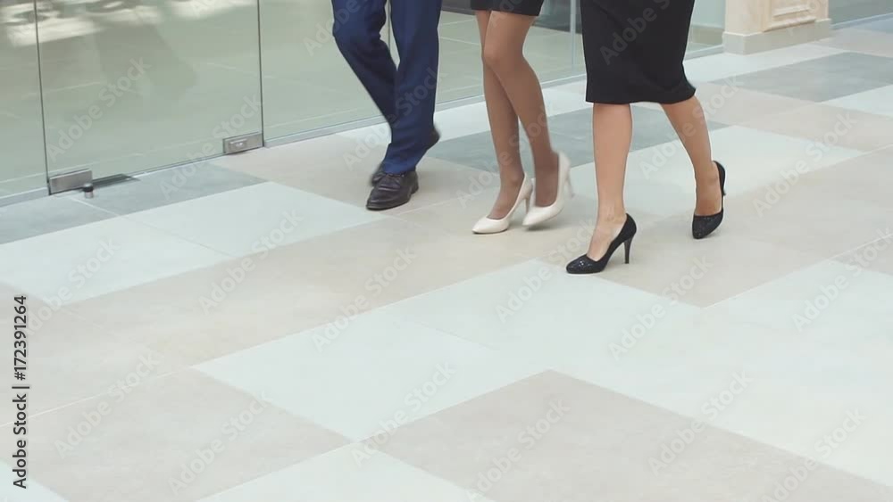Cheerful business people walking together along the office corridor. Slow motion Cheerful business people walking together along the office corridor. Slow motion