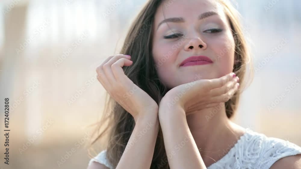 Close up portrait of beautiful young woman running hand through hair blowing in wind on tropical beach Close up portrait of beautiful young woman running hand through hair blowing in wind on tropical beach