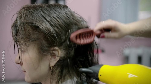 Hairdresser makes hairstyle for young girl. hairdresser uses the hair dryer