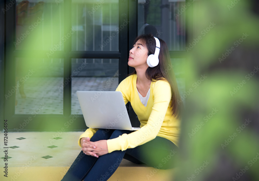 Fototapeta premium Lifestyle Girl enjoy listening music and play laptop in the nature park. Music and Lifestyle Concept.