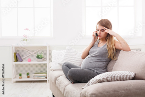 Worried pregnant woman talking on phone