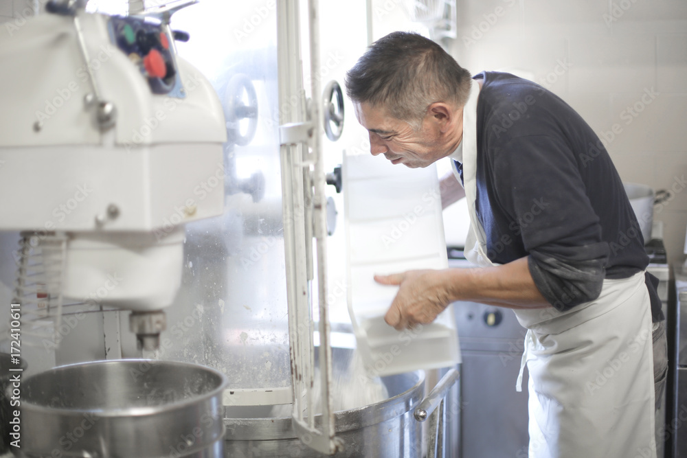 Pastry chef putting flour in a machine Pastry chef putting flour in a machine