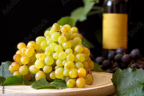 Grapes on wooden table. Branch of ripe white grapes.