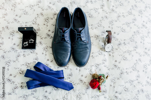 Groom's shoes and cufflinks, blue tie, wristwatch, boutonniere on a light background. Wedding concept. photo