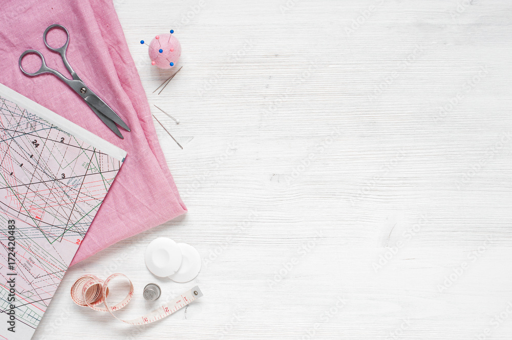 Pink natural fabric and sewing tools on  the white wooden table - obrazy, fototapety, plakaty 