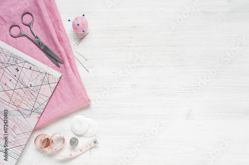 Pink natural fabric and sewing tools on the white wooden table