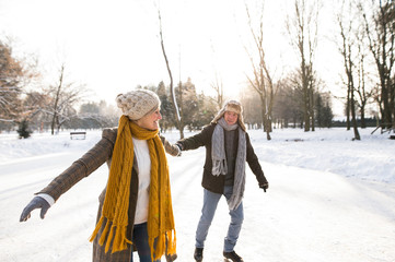 Senior couple in sunny winter nature ice skating.