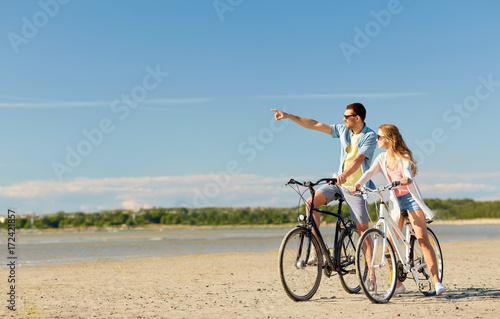 happy young couple riding bicycles at seaside