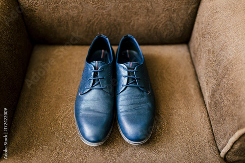 Groom's blue shoes on a brown armchair. Wedding concept. Artwork, soft focus photo