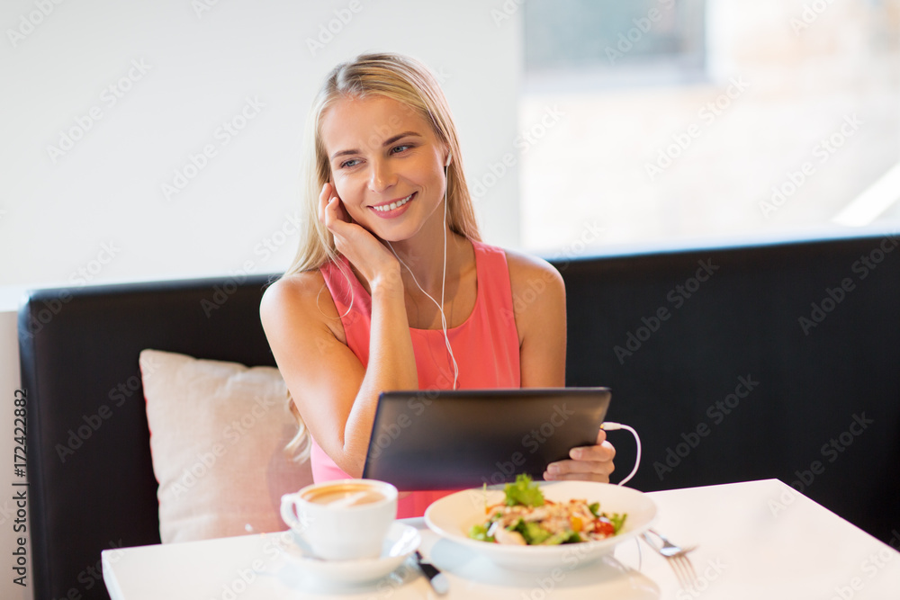 happy young woman with tablet pc at restaurant